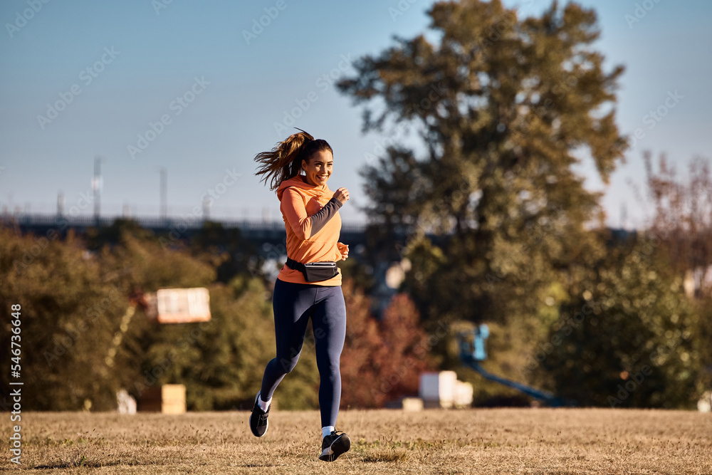 Young happy female athlete running in park.