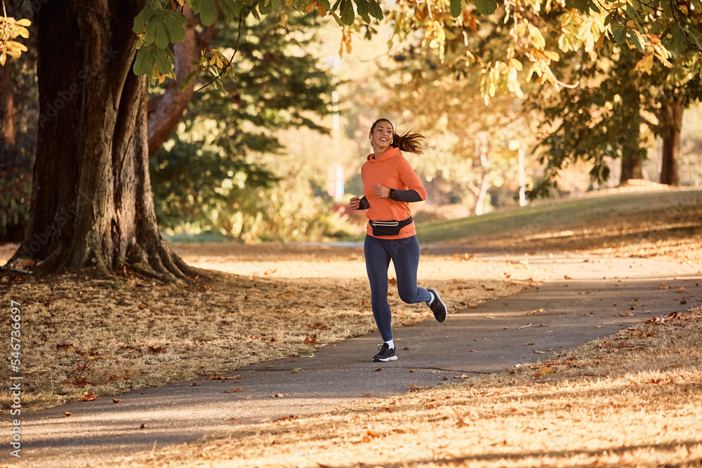Fototapeta premium Happy sportswoman running during autumn day in nature.