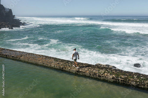 man walking along the edge of a natural pool by the sea