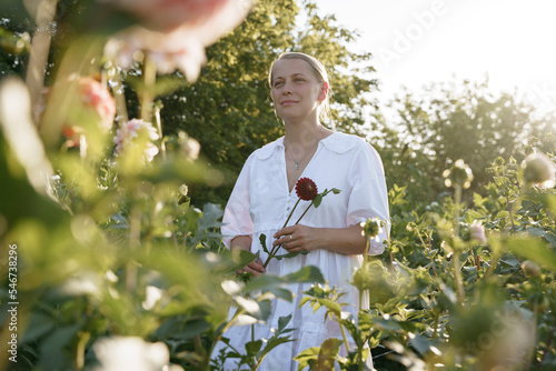 A woman flower farmer stands at sunset