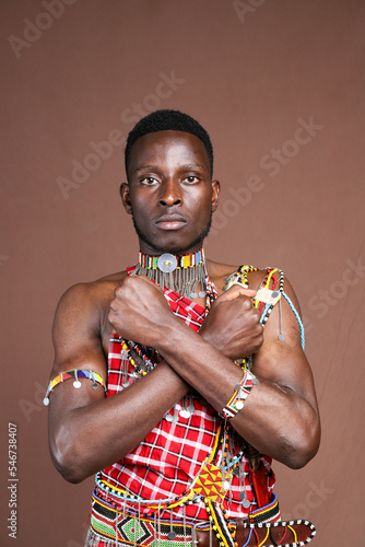 Masai warrior with arms crossed in an X.Brown background mockup space 