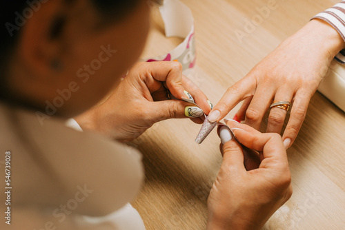 Female client getting nail extention by professional nail artist photo