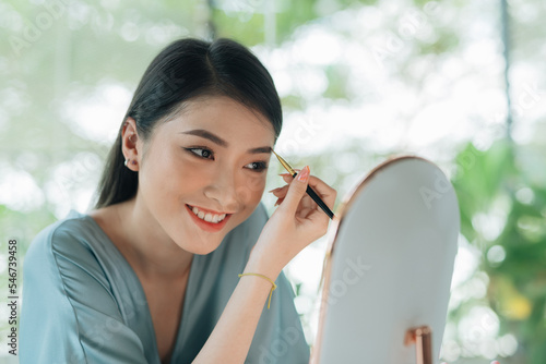 Asian woman drawing eyebrow to her face. photo