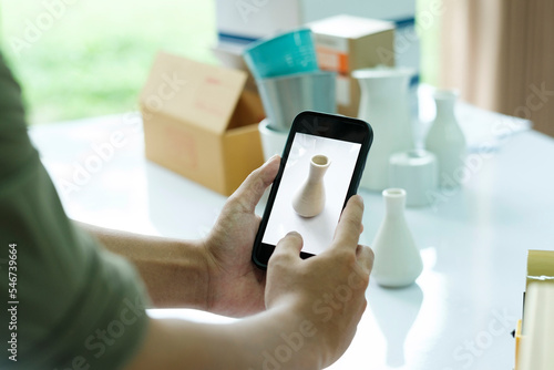 Young male online business owner using cellphone checking parcel box.