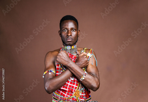Masai moran warrior with arms crossed in an X.Brown background mockup space.Copy text and paste 