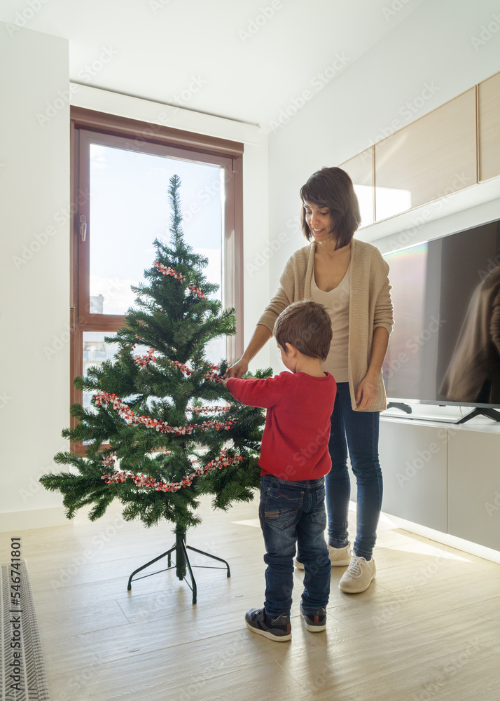 Mother and son decorating artificial christmas tree Mother and son decorating artificial christmas tree