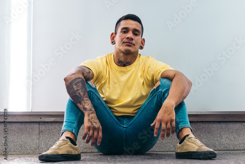 Tattooed latin man sitting on the floor with cocky attitude photo