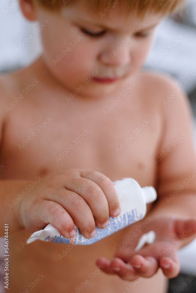 Toddler putting sunscreen on his hand Toddler putting sunscreen on his hand