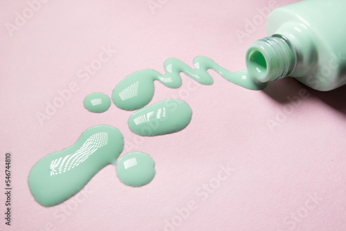 pastel green nail polish spill on pink background