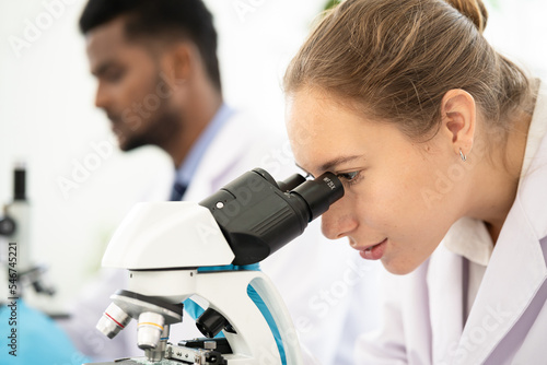 Group of Microbiologist Looking at a Lab-Grown Cultured Vegan Meat Sample in a Microscope. Medical Scientist Working on Plant-Based. medical biotechnology research laboratory using microscope.