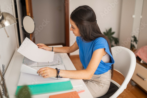 teenage girl studying at her bedroom desk photo