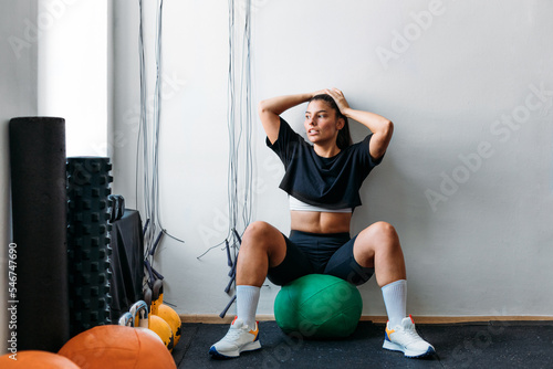 Woman Sitting on Medicine Ball in Gym photo