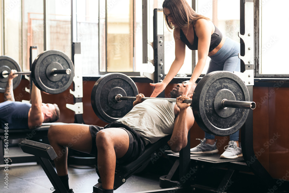 Young man training in the gym with the help of a spotter Young man training in the gym with the help of a spotter
