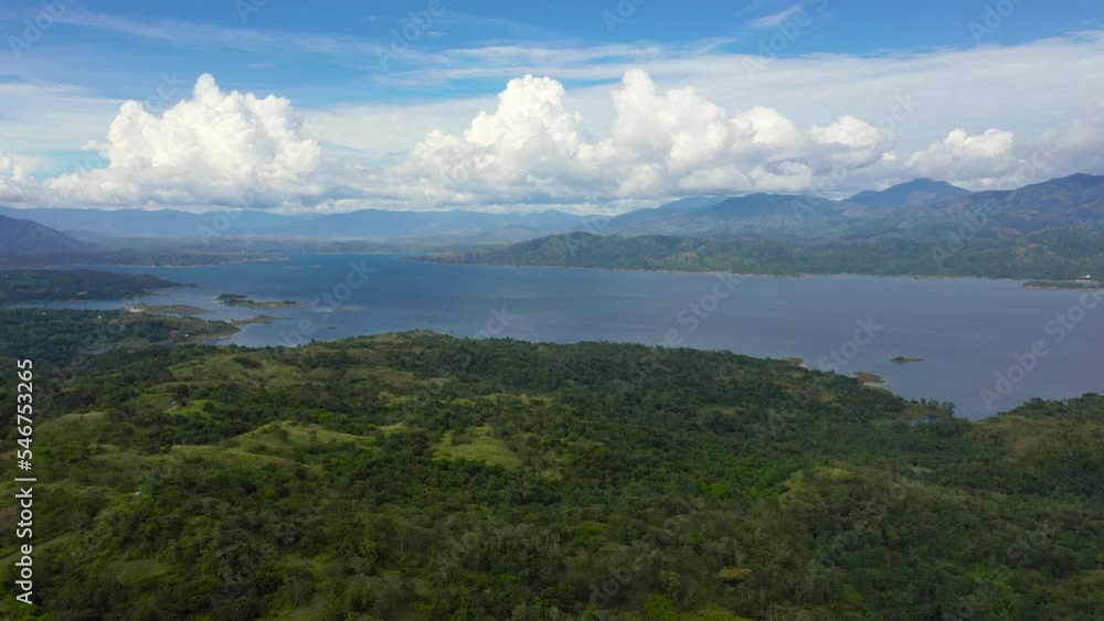Clouds over a blue lake among green hills and mountains covered with rainforest. Aerial view: Pantabangan Lake. Philippines, Luzon. Clouds over a blue lake among green hills and mountains covered with rainforest. Aerial view: Pantabangan Lake. Philippines, Luzon.