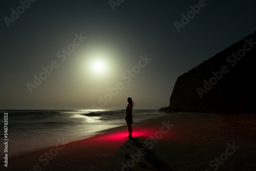 Surreal standing woman on the shore at night photo