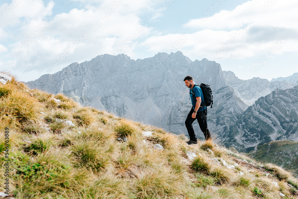 Hiker Walking Up Steep Slope In Mountain Landscpe. Hiker Walking Up Steep Slope In Mountain Landscpe.
