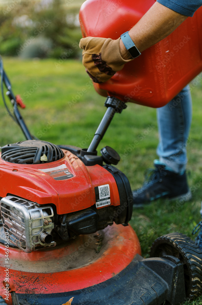 middle aged woman putting gasoline in her lawnmower middle aged woman putting gasoline in her lawnmower