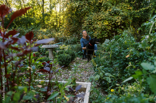 Smiling Middle-Aged Woman in the garden with her dog photo