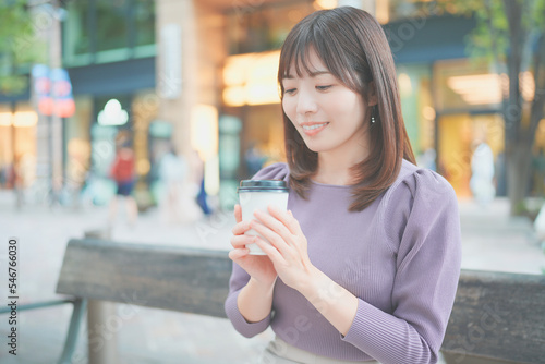 ベンチに座ってコーヒーを飲む女性