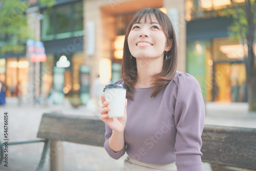 ベンチに座ってコーヒーを飲む女性