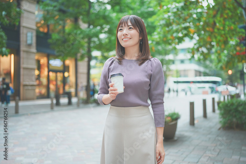 コーヒーカップを持って街を歩く女性