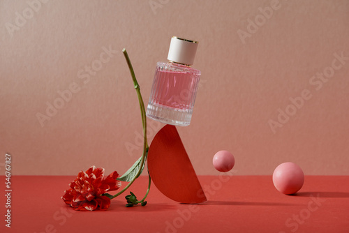 Pink perfume bottle balanced on top of flower on a table photo