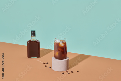 Cold brew coffee bottle and ice on glass on wooden tray photo