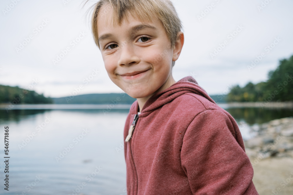 Little boy in hoodie by a northeast shore smiling Little boy in hoodie by a northeast shore smiling