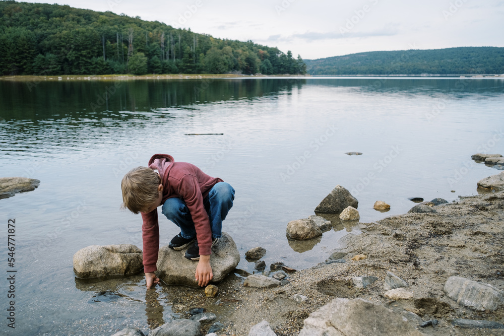 Little boy sitting on a rock in a lake and playing in water Stock Photo ...