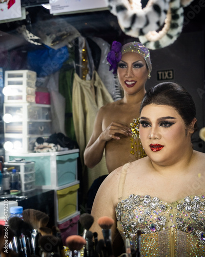 Drag queens smiling in a mirror after completing their makeup together photo