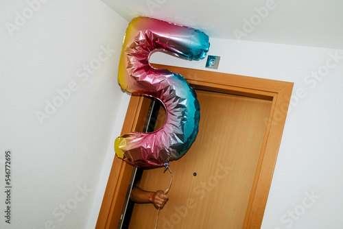 holding a 5 number-shaped balloon ouf of the door photo