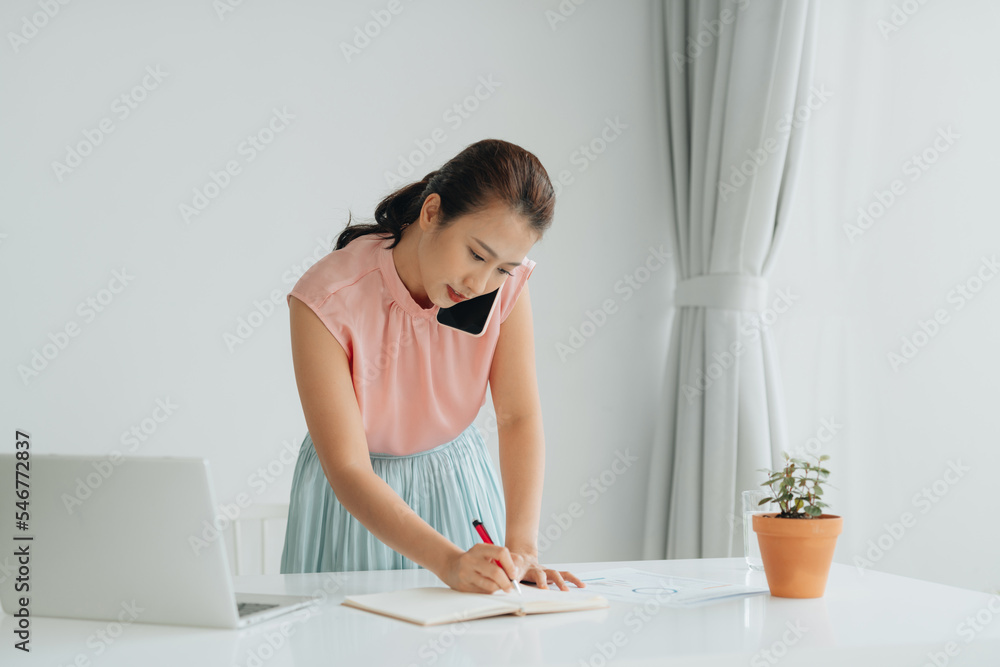 Female office employee is standing near workplace, talking on phone Female office employee is standing near workplace, talking on phone