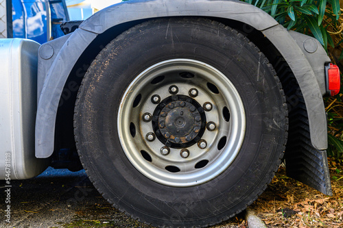 close-up of the wheel of a large freight truck, the dark center, the silver rim and the black rubber. Last wheel of the tractor head of a transport truck