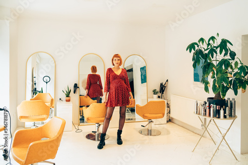 Portrait of Pretty Pregnant Hairdresser in Her Salon photo