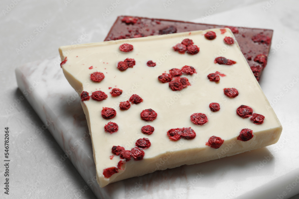 Board and different chocolate bars with freeze dried fruits on light marble table, closeup Board and different chocolate bars with freeze dried fruits on light marble table, closeup