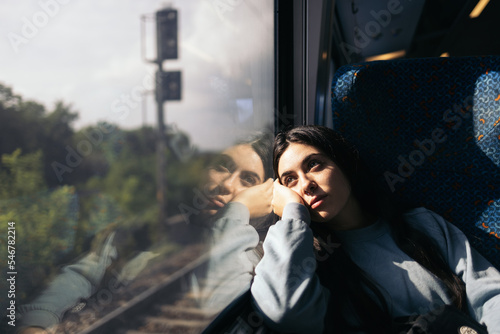 Young woman traveling by train looking out the window photo