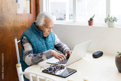 Old man working from home with laptop and tablet photo