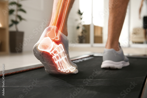 Digital composite of highlighted bones and man training on walking treadmill at home, closeup © New Africa