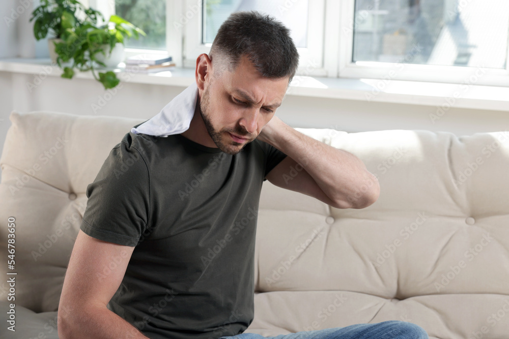 Man using heating pad on sofa at home Man using heating pad on sofa at home
