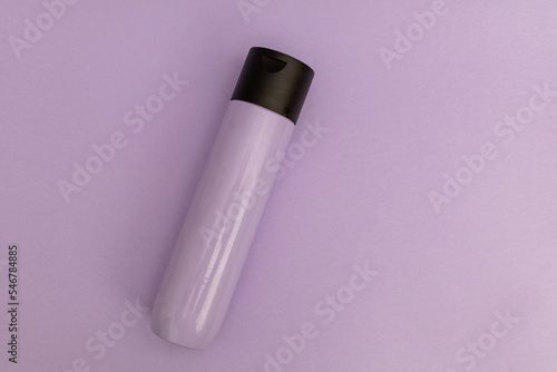Shampoo for hair in a stylish purple plastic jar on purple background, monochrome items