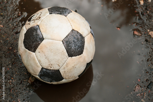 Dirty soccer ball in muddy puddle, closeup © New Africa