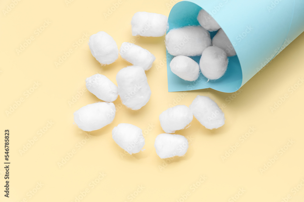 Soft cotton balls with paper cone on beige background Soft cotton balls with paper cone on beige background