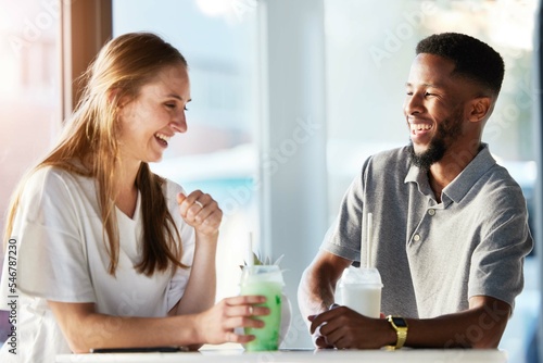 Restaurant, dating and couple drink smoothie and having conversation, talking and chatting. Love, relationship and man and woman sitting in urban cafe enjoying juice, laughing and speaking together