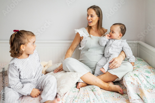 pregnant mom playing with her two little sons in the bedroom photo
