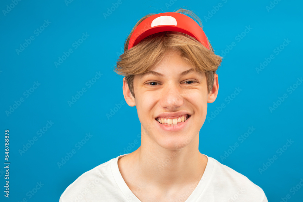 Let me think. Portrait of a cheerful handsome seller wearing a white t-shirt and a visor on his head in studio on a blue background Let me think. Portrait of a cheerful handsome seller wearing a white t-shirt and a visor on his head in studio on a blue background