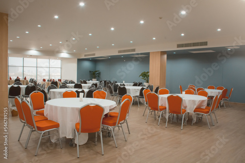 Valokuva Round table with a white tablecloth, orange and black chairs in a modern restaurant or banquet room of a luxury hotel