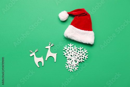 Santa hat with beard made of snowflakes and reindeers on green background