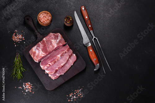 Fresh piece of raw pork with spices, salt and herbs on a wooden cutting board