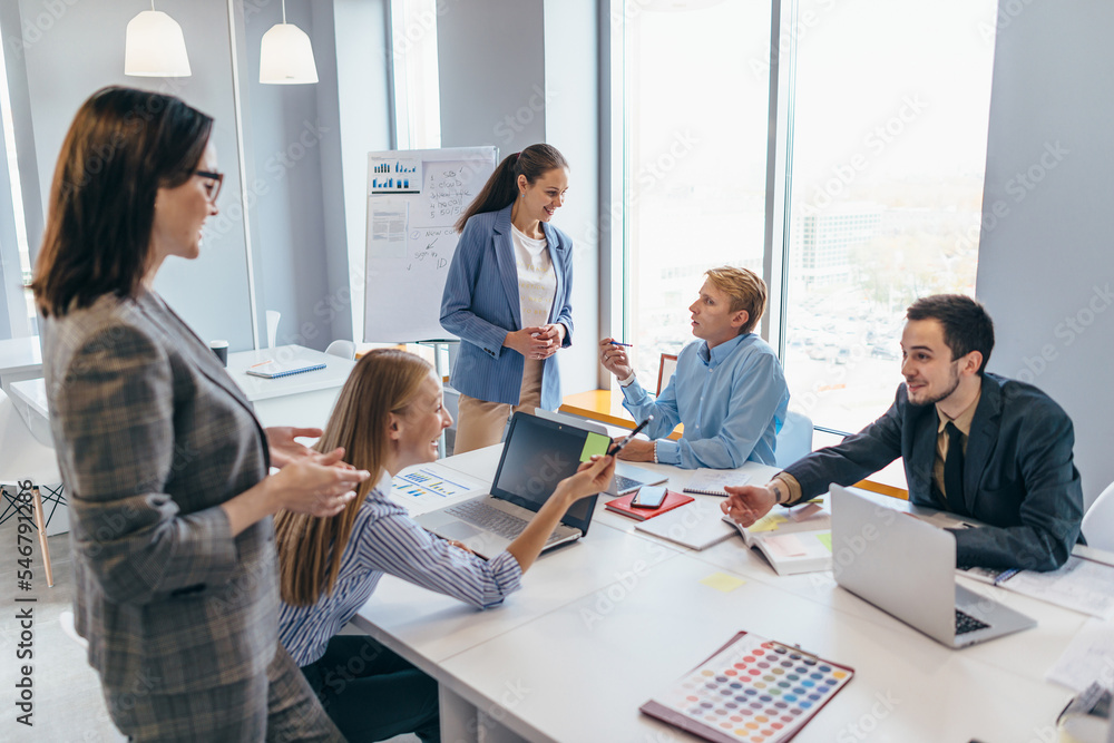 Coworkers discussing business ideas while working in office Coworkers discussing business ideas while working in office