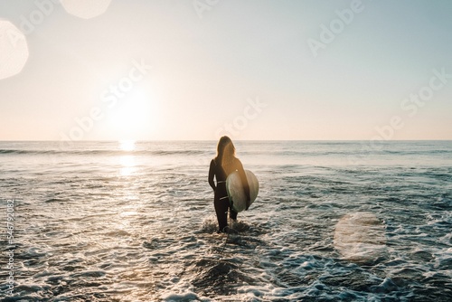 Female surfer surfing with a longboard at the Cordoama Beach on a sunny day in Algarve, Portugal photo